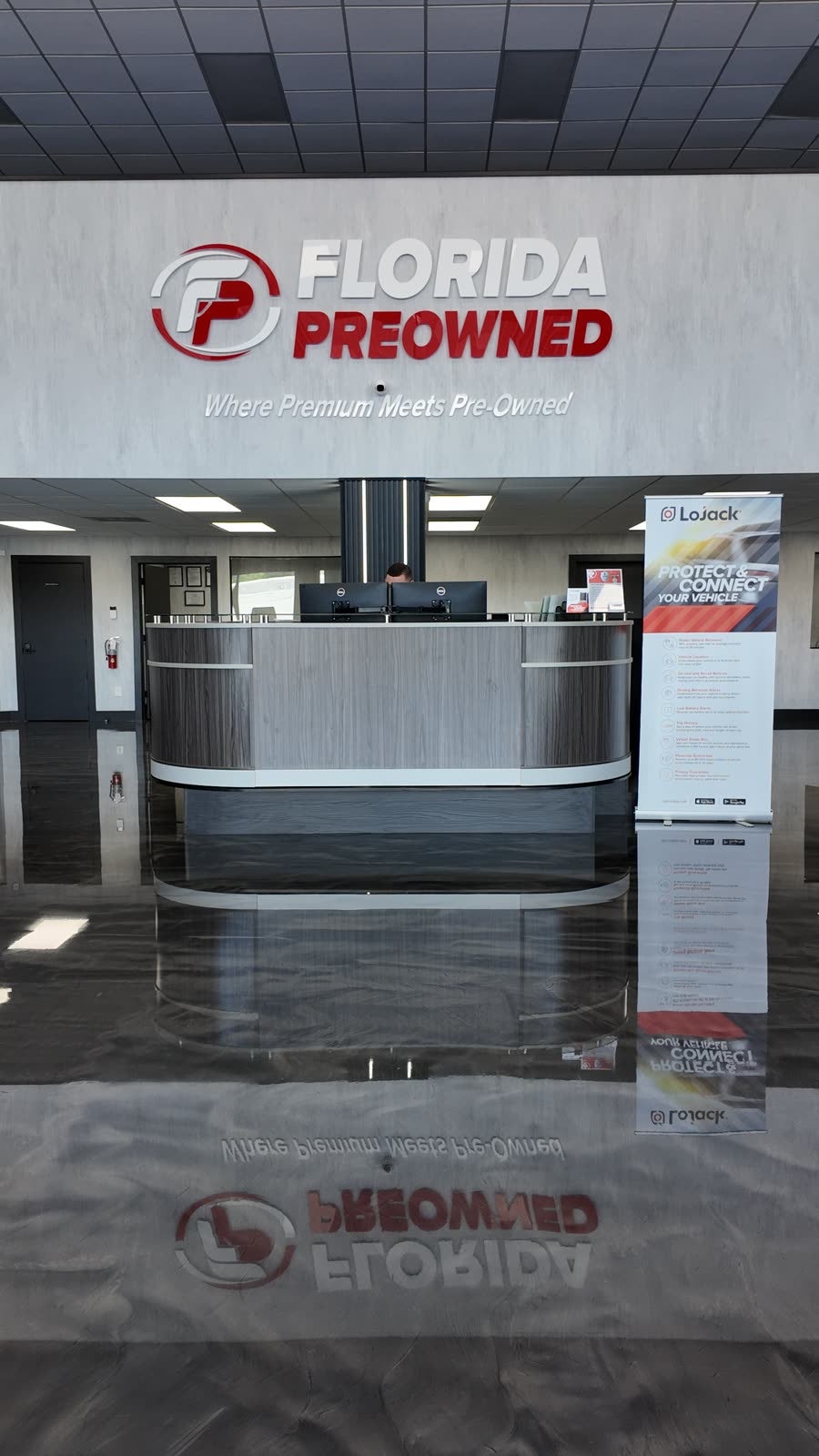 Florida Preowned reception at 3450 W Colonial Drive, Orlando, FL 32808 — branded welcome desk under the Florida Preowned logo with the tagline 'Where Premium Meets Pre-Owned' on a polished marble floor.