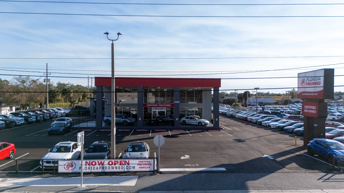 Florida Preowned storefront at 3450 W Colonial Drive (Highway 50), Orlando, FL 32808 — pre-owned trucks, SUVs, and certified vehicles on the lot with the Florida Preowned sign and Certified Pre-Owned tower visible from the street.