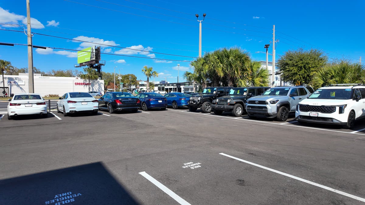 Florida Preowned luxury pre-owned inventory at 3450 W Colonial Drive, Orlando, FL 32808 — pre-owned BMW, Genesis, Jaguar, Hyundai Palisade, and Jeep Wrangler lined up under blue Florida sky, popular among Winter Park and 32789 residents.